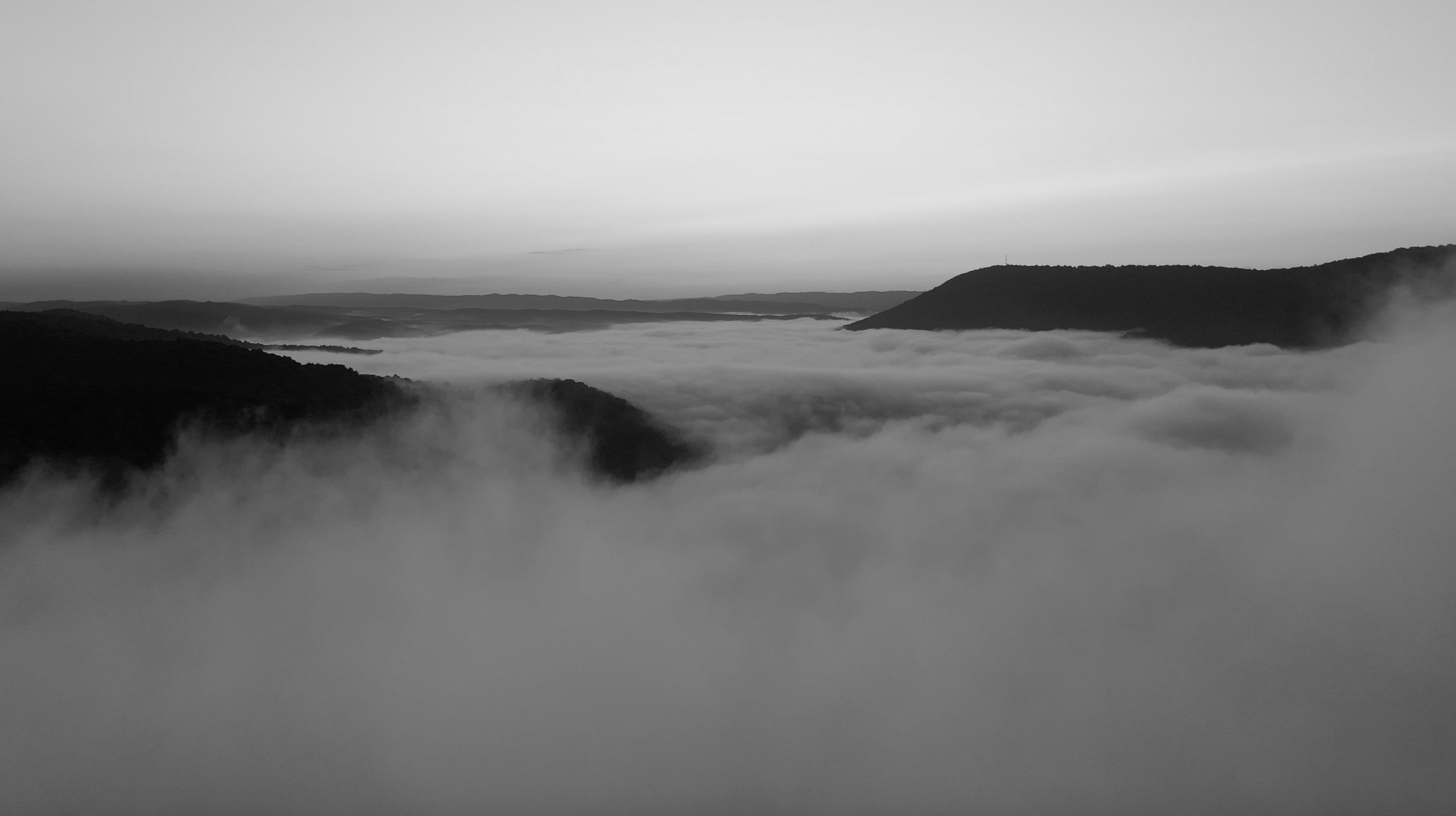 Fog over the Raystown Dam at dawn, dark ridges breaking through